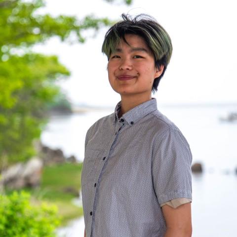 A UNE student poses in front of the Saco River on UNE's campus